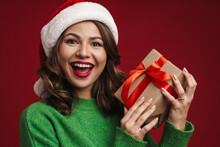 Positive Young Woman In Christmas Santa Hat Holding Present