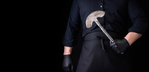 Wall Mural - man in black clothes, latex gloves holds a vintage metal ax-knife for meat and vegetables