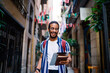 © BullRun - Happy ethnic male student walking on street in daytime