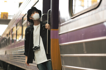 Wall Mural - Asian travelers men and camera in train station with medical face mask to protection the Covid-19, new normal lifestyle