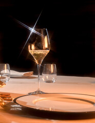 glass of champagne on table setting at restaurant, star light reflections on black background