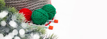 Green And Red Yarn In A Knitted Gray Basket On A White Table. Home Comfort And Christmas Concept. Women's And Men's Hobby Knitting.