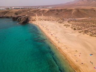 Wall Mural - Aerial view of the jagged shores and beaches of Lanzarote, Spain, Canary. Roads and dirt paths. Walking routes to explore the island. Bathers on the beach. Atlantic Ocean. Papagayo
