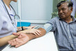 © Pituk - Young Asian nurse measuring blood pressure of elderly man, selective focus point