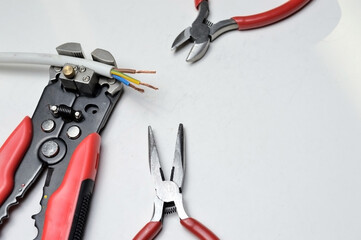 wire stripper, shielded three-core wire and wire cutters on a white background. close-up