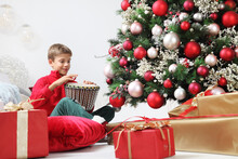 Merry Christmas And Happy Holidays, Child Stay At Home Plays The Drum Near The Illuminated And Decorated Tree And Wrapped Gift Packages