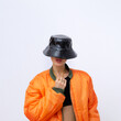 © Porechenskaya - Girl in fashion urban street outfit. Trendy orange bomber jacket and stylish black bucket hat. Fall winter seasons lookbook. Style in details