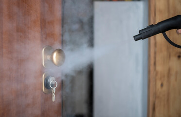 disinfection and sanitization with steam at home, steam flow is directed to the door handle and keys in the lock