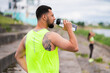 © Georgii - Handsome young athletic guy in stylish sportswear drink water during workout in urban