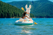Teen girl paddling on lake in inflatable llama pool floaty
