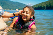 © Inti St. Clair - Mom touching hair of smiling girl in lifejacket swimming in lake
