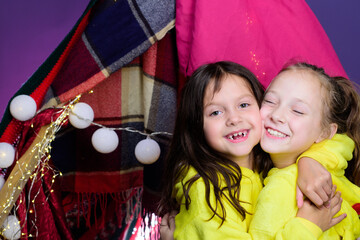 Funny kids face of two cute little children playing in tent at home. Funny lovely kids having fun. Pajamas for kids. Girls having fun tipi house. Girlish leisure.