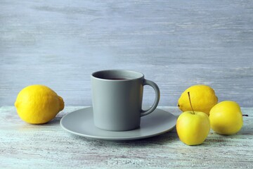 Hot tea in a large cup, lemons and apples on a wooden windowsill, the concept of a vitamin drink for colds, home comfort