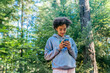 © Inti St. Clair - Smiling teen girl playing on cell phone outside in nature