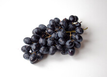 A Handful Of Black Grapes On A White Background