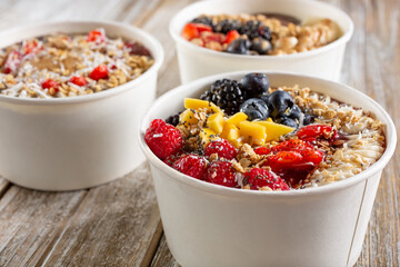 A view of a three acai bowls on a wood surface.