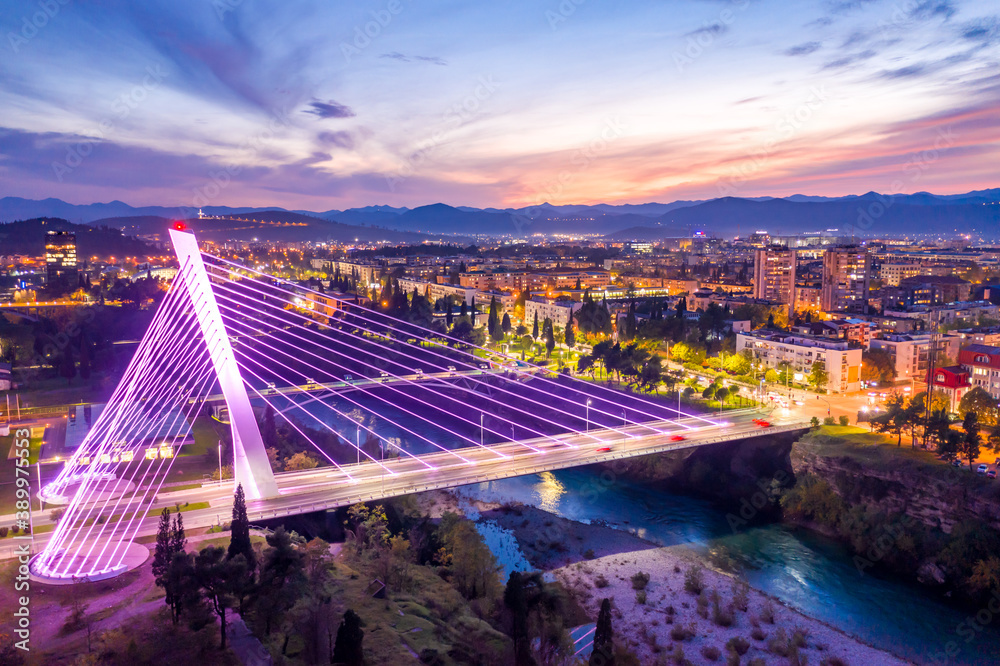Obraz na płótnie Podgorica, Montenegro, at night, featuring illuminated Millennium bridge in the city center, under colorful sunset sky. Cityscape of the capital of a small country in the Balkans, south east Europe. w salonie