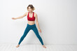 © SHOTPRIME STUDIO - sports woman in a bright room doing yoga in full growth blue leggings and a red tank top