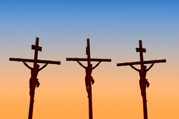 Three crosses with crucified silhouettes. Sunset. Calvary or Golgotha