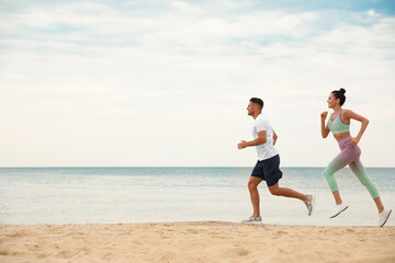 Canvas Print - Couple running together on beach, space for text. Body training