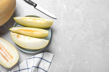 Pieces of delicious honeydew melon on light grey marble table, flat lay. Space for text