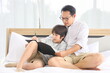 © Akarawut - Asian father teaching homework to his son in bed for homeschooling and education concept