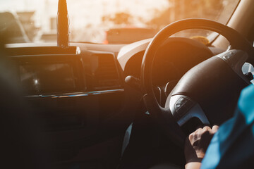 A man holding the steering wheel of a car while driving There is a background, a windshield and a road, a close-up shot of a man driving to work.