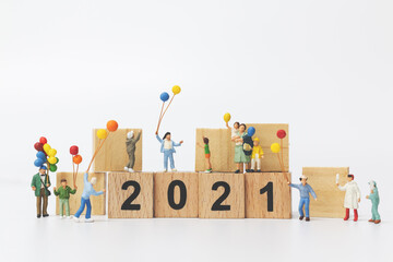 Miniature people : Happy family holding balloon on wooden block number 2021