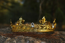 Mysterious And Magical Photo Of Gold King Crown In The England Woods Over Stone. Medieval Period Concept.