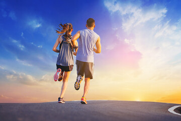 Wall Mural - Young couples running sprinting on road. Fit runner fitness runner during outdoor workout with sunset background.