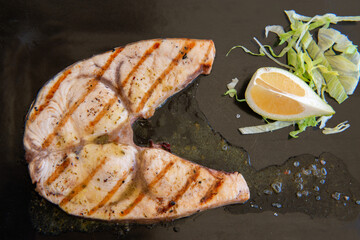 Cooked swordfish. Grilled slice of fish with lemon and salsd on plate in restaurant