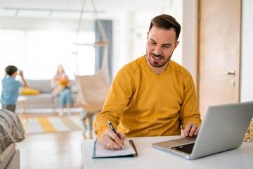 Work from home. Man works on laptop with family playing around