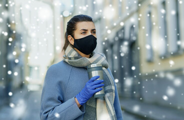 Wall Mural - health, safety and pandemic concept - young woman wearing black face protective reusable barrier mask with tumbler or thermo cup on city street over snow