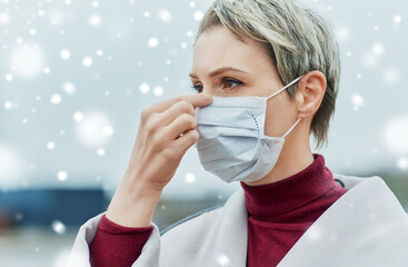 Wall Mural - health, safety and pandemic concept - young woman wearing protective medical mask outdoors over snow