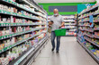 © Анна Демидова - A masked man with a phone in a supermarket walks between the shelves with groceries. Coronavirus pandemic.