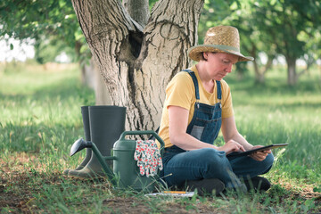 Wall Mural - Female farmer using digital tablet in walnut orchard, innovative technology in organic farming