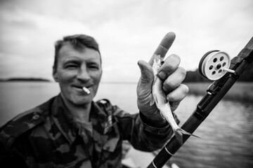 Wall Mural - Man fishing rod on the river on a rubber boat. Black and white photo.