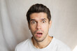 Portrait of a young cute man with a shocked surprised face expression and wide open eyes 