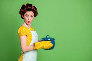 Sticker - Profile side photo of astonished cute girl hold prepare organic tasty soup hold saucepan wear yellow pot holder dotted skirt dress hair rollers isolated over green color background