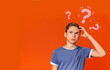Pensive teenager searching for solution to problem on orange background, collage with question marks. Copy space