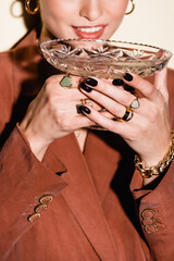 Wall Mural - cropped view of happy woman in brown blazer drinking champagne from glass on white