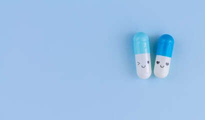 Two capsules with funny faces on blue background top view