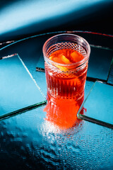 mixed alcohol cocktail with whiskey near mirrors on surface and blue background