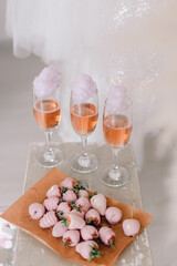 Three glasses of rose wine and cotton candy near fruit dessert