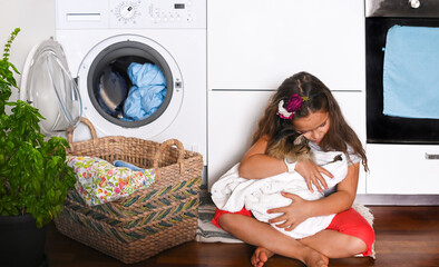 Little beautiful girl washes and plays with kitten B, she dries him with a towel after washing. The child sits on the floor near the washing machine. Banner. Long format. High quality photo