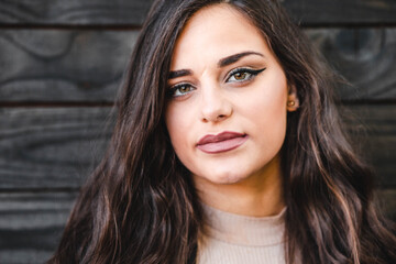 Portrait of a beautiful brunette teenage girl with hazel eyes, looking straight up to the camera, full of confident