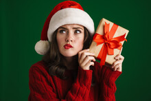 Charming Brooding Girl In Santa Claus Hat Posing With Christmas Gift