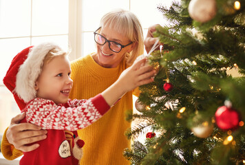 Wall Mural - happy family grandmother and grandson decorate the Christmas tree for the holiday.