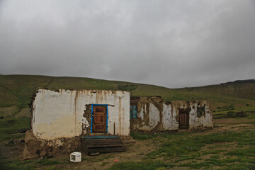 Poster - Old weathered house in a hilly green landscape during a foggy weather