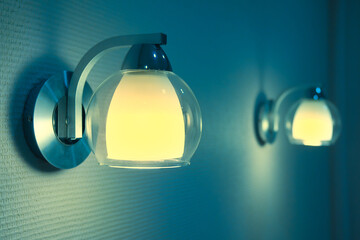 Pair of lamps lights in bedroom. The blue and yellow tone image of two night lamps.